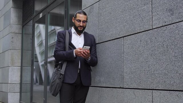 Self confident man in eyeglasses scrolling web-pages on smartphone ordering taxi