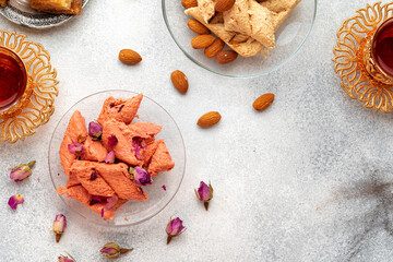 Assortment of Turkish delights with glass of tea on gray background