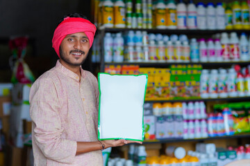 Indian farmer showing fertilizer bag at fertilizer shop.