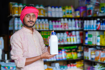 Indian farmer showing liquid fertilizer bottle at shop