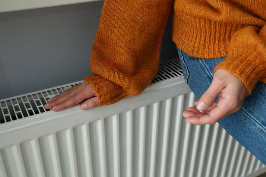 Concept of heating season with girl sitting on radiator