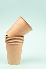 Set of disposable paper cups stacked in a row for drinks on a colorful background. Vertical photo