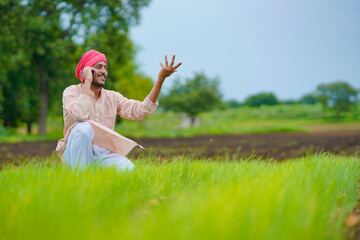 Indian farmer talking on smartphone at agriculture field.