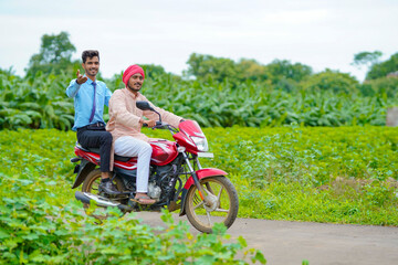 Indian agronomist going agriculture field with farmer on bike.