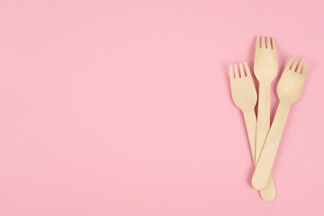 Eco-friendly tableware, wooden forks on a pink background. Copy space