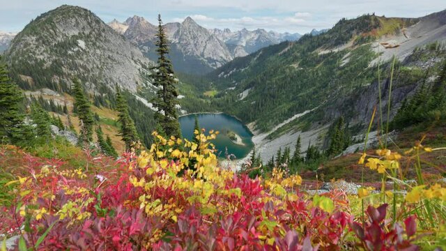 Red-yellow leaves on the background of the mighty mountain peaks. Mountains and lake in North Cascades national park, USA. Autumn in the mountains. Nature of the United States of America, gimbal shot