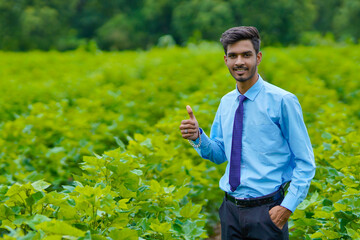 Young indian agronomist standing at agriculture field.