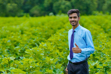 Young indian agronomist standing at agriculture field.