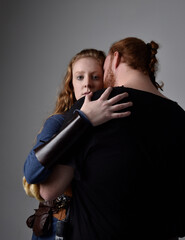 Full length  portrait of red haired  couple, man and woman wearing medieval viking inspired fantasy costumes, standing romantic intimate poses, isolated on white  studio background.