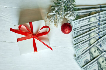 Christmas Gift box and US dollar bills on white wooden background