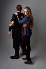 Full length  portrait of red haired  couple, man and woman wearing medieval viking inspired fantasy costumes, standing romantic intimate poses, isolated on white  studio background.