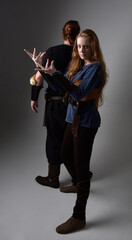 Full length  portrait of red haired  couple, man and woman wearing medieval viking inspired fantasy costumes, standing romantic intimate poses, isolated on white  studio background.