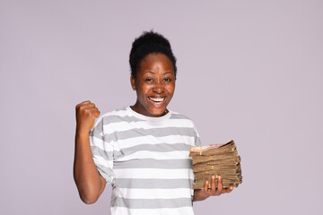 excited young black woman rejoicing while holding some cash