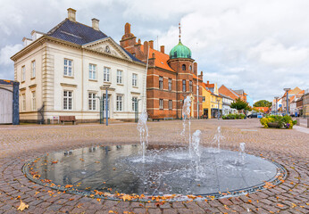 Town square at Stege on the island of Møn, Denmark, with fountain, town hall and historic savings...