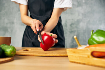 Woman in black apron on the kitchen cutting vegetables