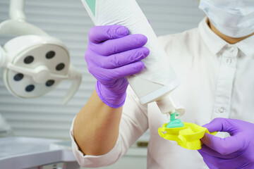 A dentist applies a remineralizing gel to a yellow spoon. Prevention of caries