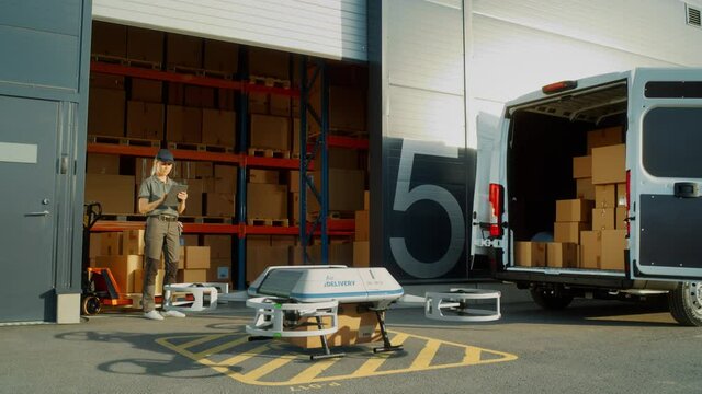 Storage Facility Female Worker Uses Tablet Computer to Send Autonomous Flying Delivery Drone with a Parcel. Futuristic Parcel Drone Takes Off on Flight from Warehouse to Client Waiting for Package