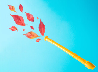 Creative autumn layout with yellow plastic flute and red leaves on cyan blue background.Trendy fall...