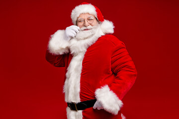 Photo of funky positive retired man wear santa claus costume belt spectacles smiling arm mustaches isolated red color background