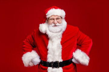 Naklejka premium Photo of funny funky retired man wear santa claus costume cap spectacles smiling arms hands waist isolated red color background