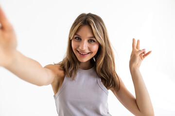 Fototapeta premium Portrait of a smiling cute woman making selfie photo on phone isolated on a white background