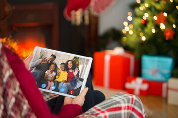 Naklejka na ściany i meble Caucasian woman making christmas tablet video call with waving african american family