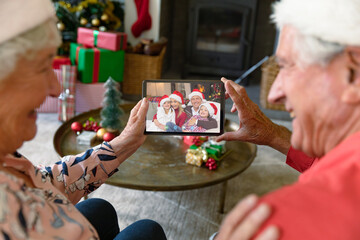 Happy caucasian senior couple making tablet christmas video call with smiling family