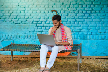 Technology concept : Indian farmer using laptop at home.