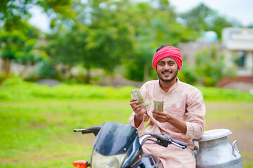 Rural scene : Indian milkman sitting on bike and showing money