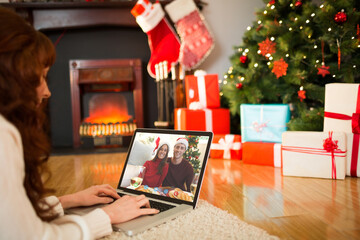 Caucasian woman on christmas laptop video call with caucasian couple