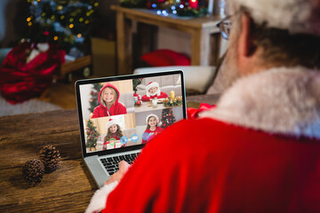 Caucasian santa claus on christmas laptop video call with caucasian group of children