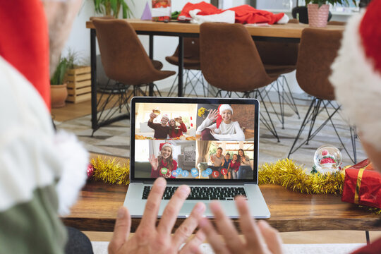 Caucasian couple on christmas laptop video call with diverse group of friends