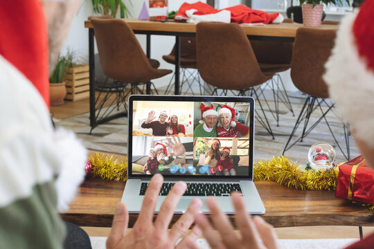 Caucasian couple on christmas laptop video call with diverse group of friends