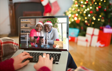Caucasian woman on christmas laptop video call with african american couple