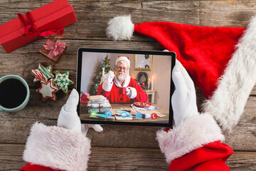 Santa claus on christmas laptop video call with caucasian santa - obrazy, fototapety, plakaty