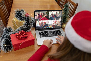Naklejka na ściany i meble Caucasian woman on christmas laptop video call with diverse group of friends