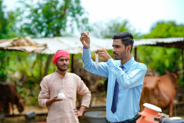 Young indian agronomist or animal doctor collecting milk sample at dairy farm