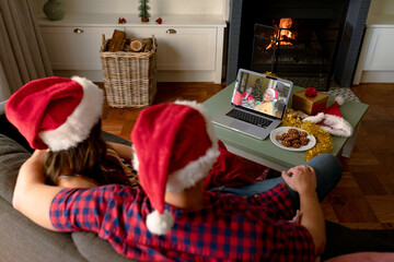 Caucasian couple in santa hats on christmas video call on laptop with senior parent