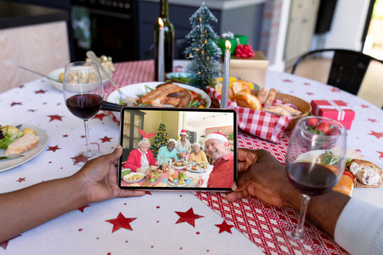 Hands Of African American Couple Holding Tablet With Caucasian Family On Screen