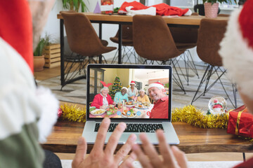 Caucasian couple in santa hat on christmas video call on laptop with senior friends