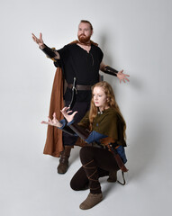 Full length  portrait of red haired  couple, man and woman wearing medieval viking inspired fantasy costumes, standing pose, isolated on white  studio background. 