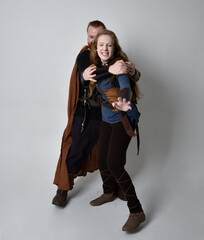 Full length  portrait of red haired  couple, man and woman wearing medieval viking inspired fantasy costumes, standing pose, isolated on white  studio background. 