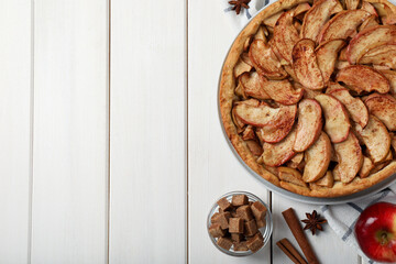 Delicious apple pie and ingredients on white wooden table, flat lay. Space for text