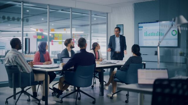 Multi-Ethnic Office Conference Room. Indian CEO does Presentation for Diverse Young Specialist, Talking, Using TV with Infographics, Statistics, Graphs. Businesspeople Develop e-Commerce Startup