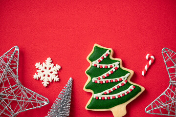 Decorated Christmas gingerbread cookies with decorations on red table background.