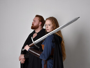 Full length  portrait of red haired  couple, man and woman wearing medieval viking inspired fantasy...