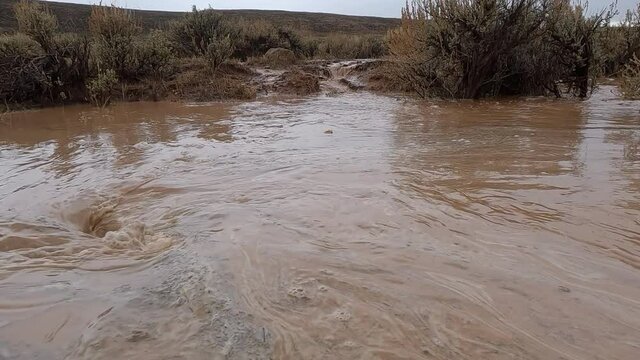 Panning over flood water being suctioned into whirlpool after rain storm in the Wyoming desert.