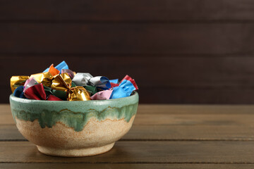 Candies in colorful wrappers on wooden table, space for text