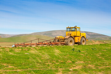Obraz premium Harvesting, the harvester machine is harvesting, plowing the land. Industrial farming and farming. Preparation for sowing seeds. Tractor at work on the field.