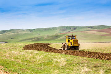 Fototapeta premium Harvesting, the harvester machine is harvesting, plowing the land. Industrial farming and farming. Preparation for sowing seeds. Tractor at work on the field.